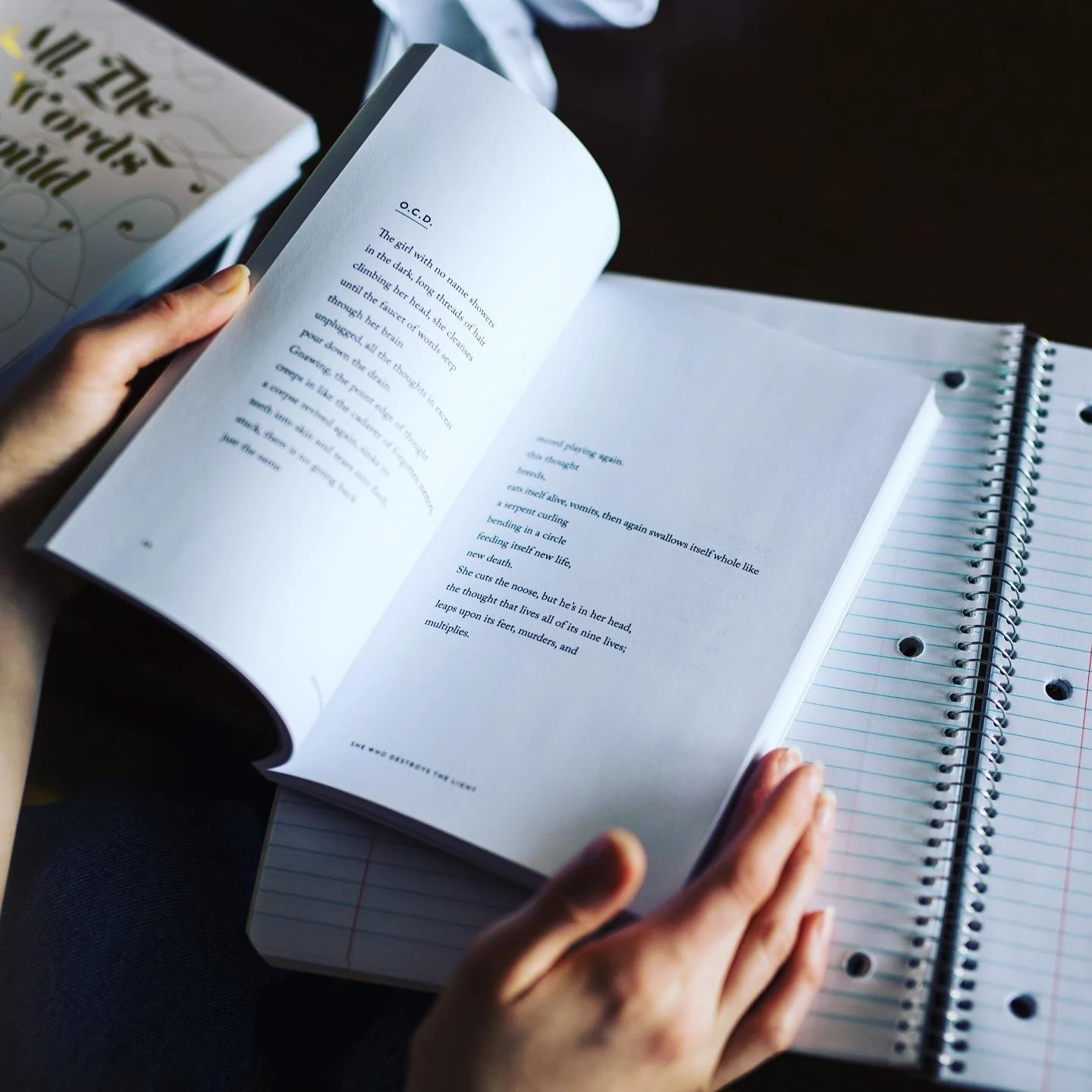 Reader studying a poetry book beside an open notebook