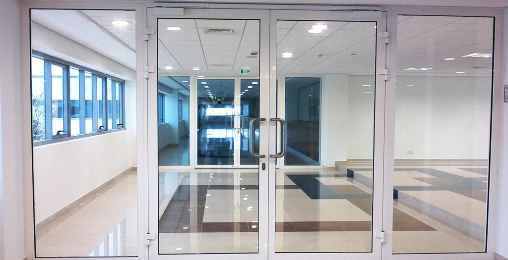 Glazed double entrance doors in a bright commercial corridor