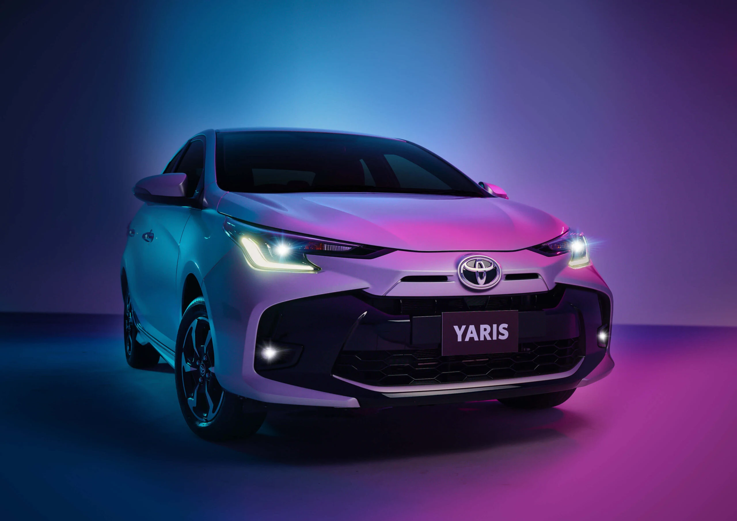 Compact Toyota Yaris photographed under blue and purple studio lighting