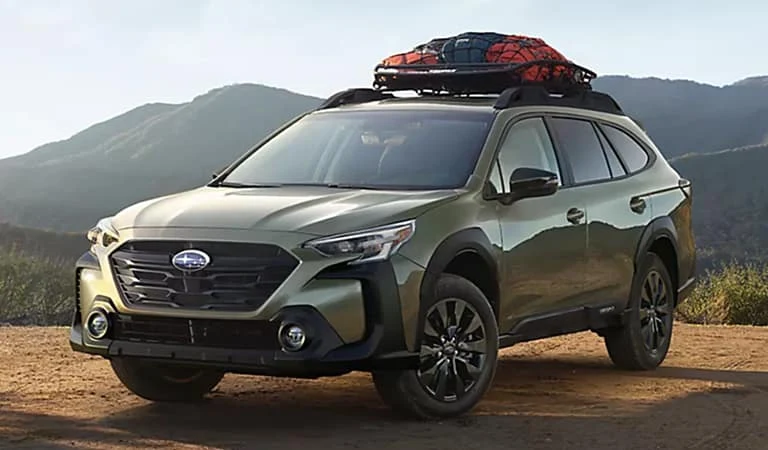 Car with a loaded roof cargo box parked beside a mountain road