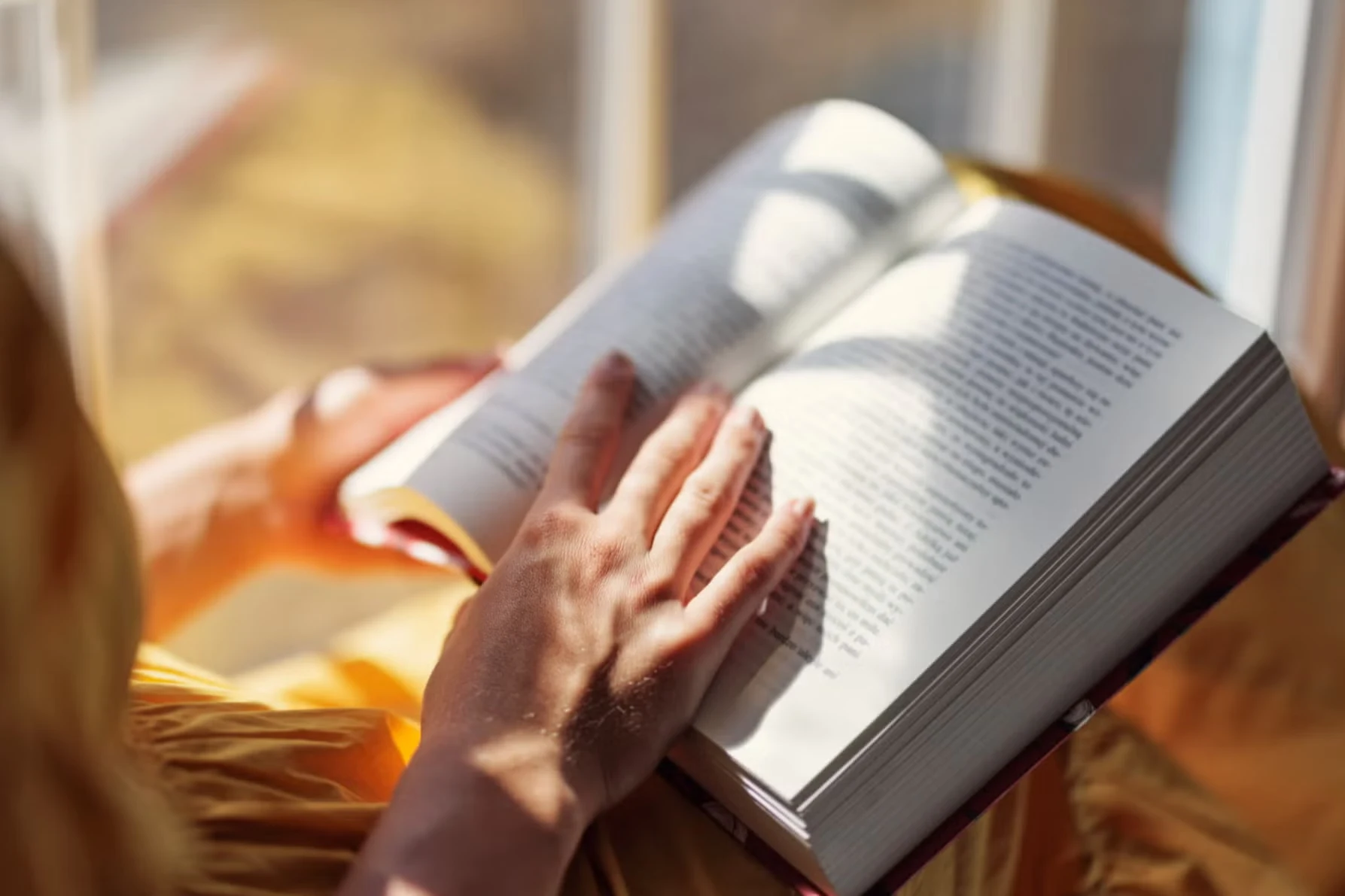 Person reading an open book in warm natural light
