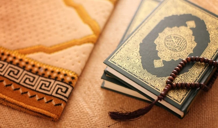 Quran with prayer beads on a prayer mat
