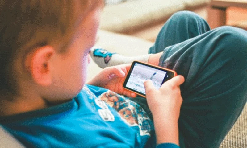Child using a mobile phone while sitting indoors.