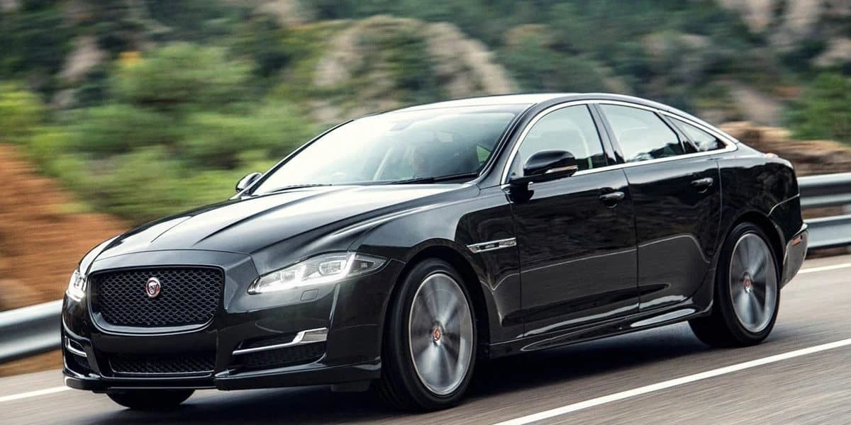 Black Jaguar luxury sedan driving on a road