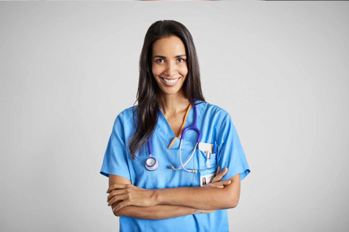 Nurse in blue scrubs standing with a stethoscope