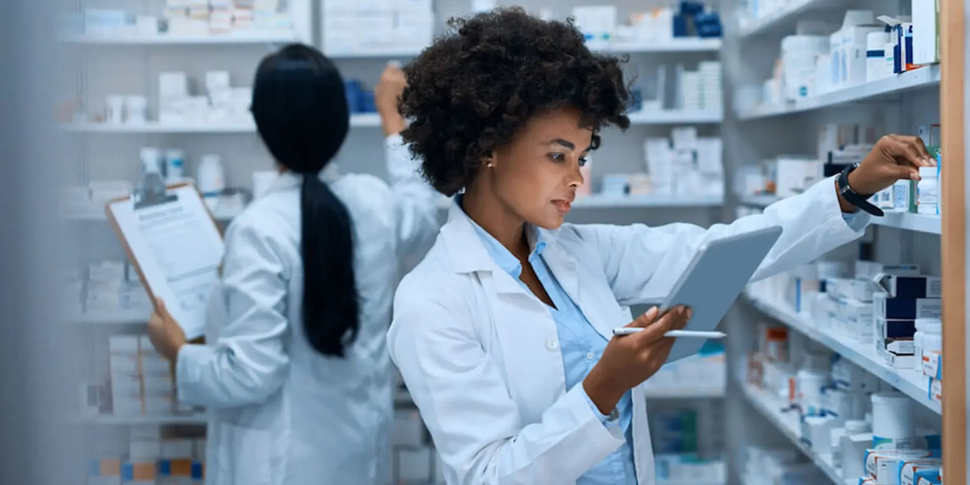 Pharmacist checking medicine stock with a tablet in a pharmacy